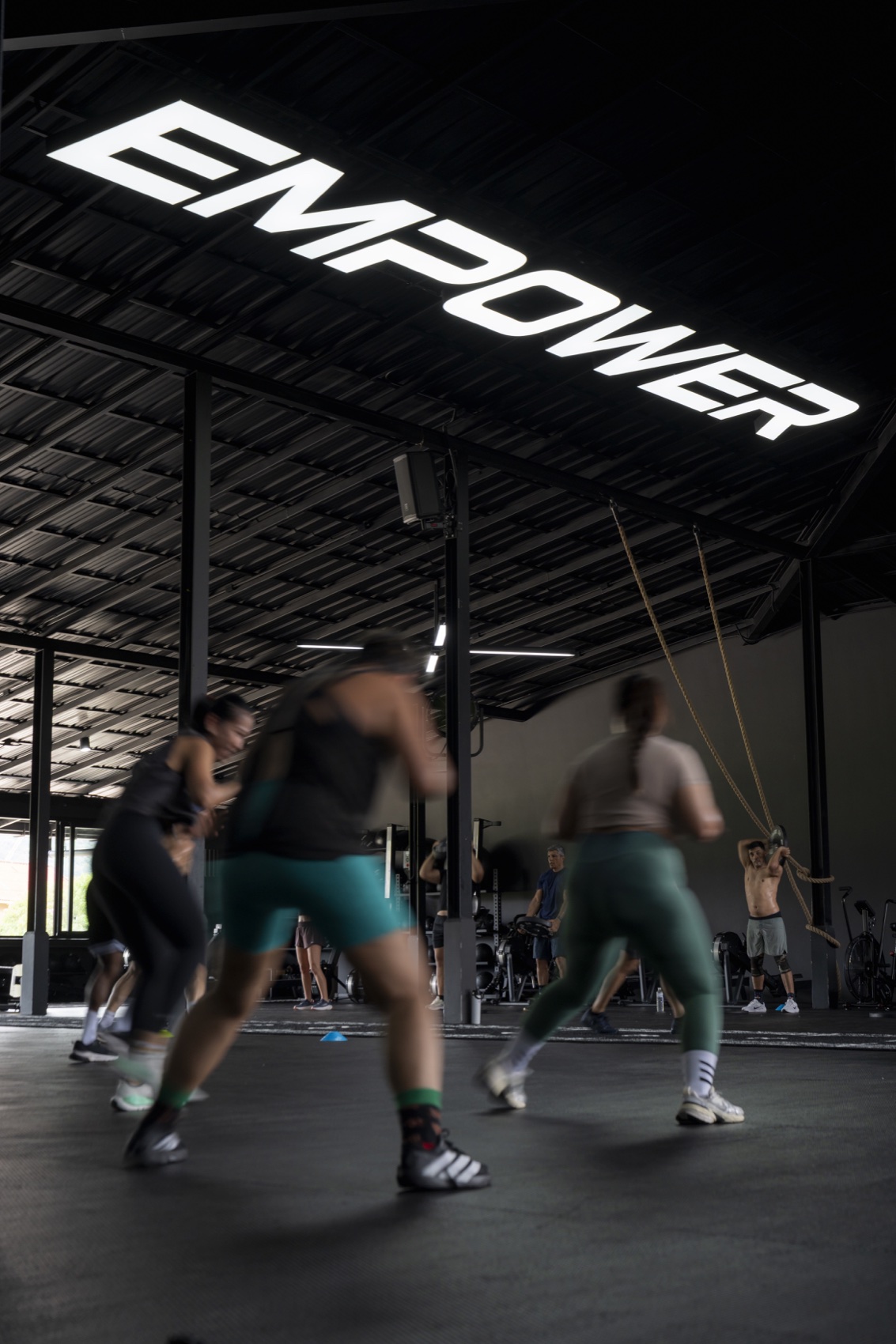 Fast-moving group HIIT class beneath the EMPOWER sign