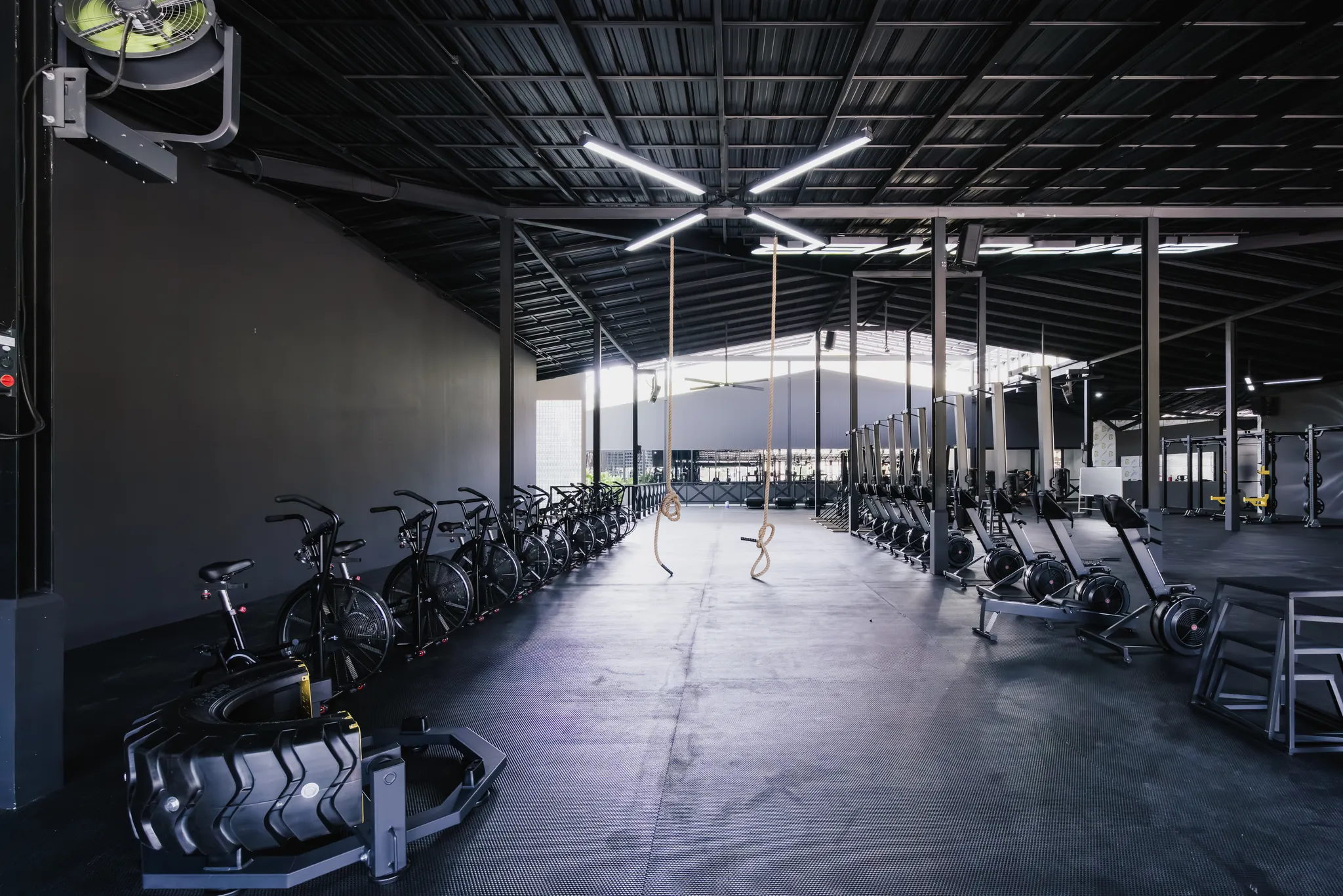 Wide view of the EMPOWER functional fitness floor with air bikes, rowers and open training space
