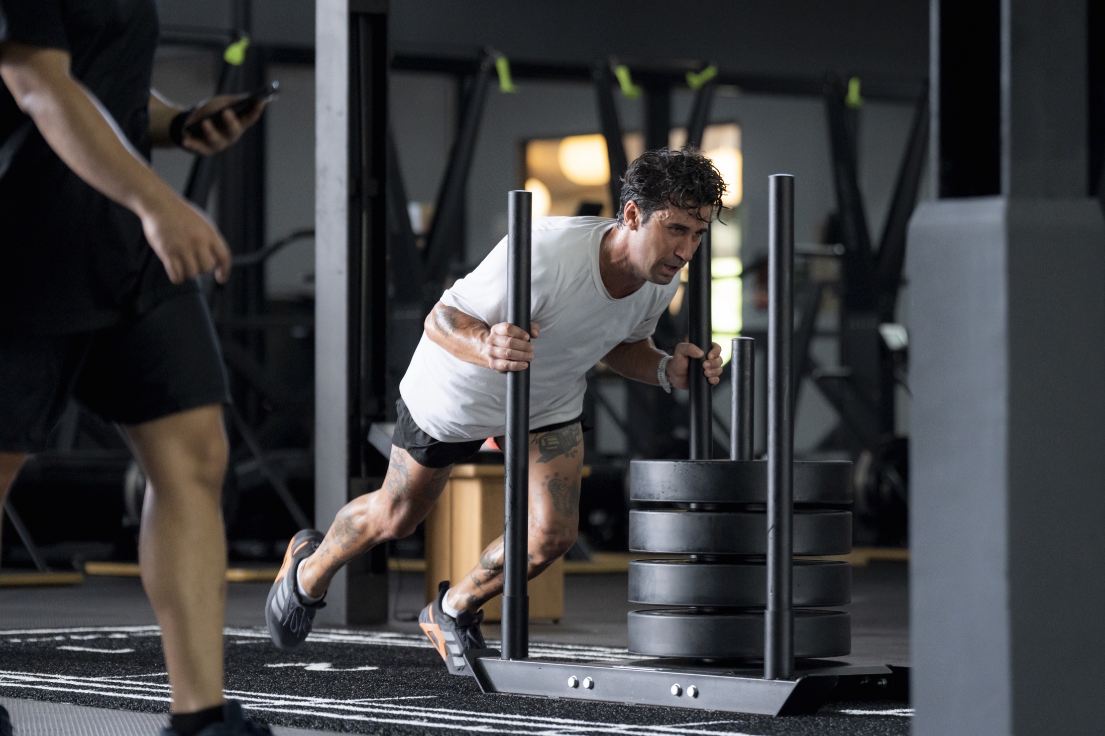 Athlete pushing a weighted sled during HYROX training at EMPOWER