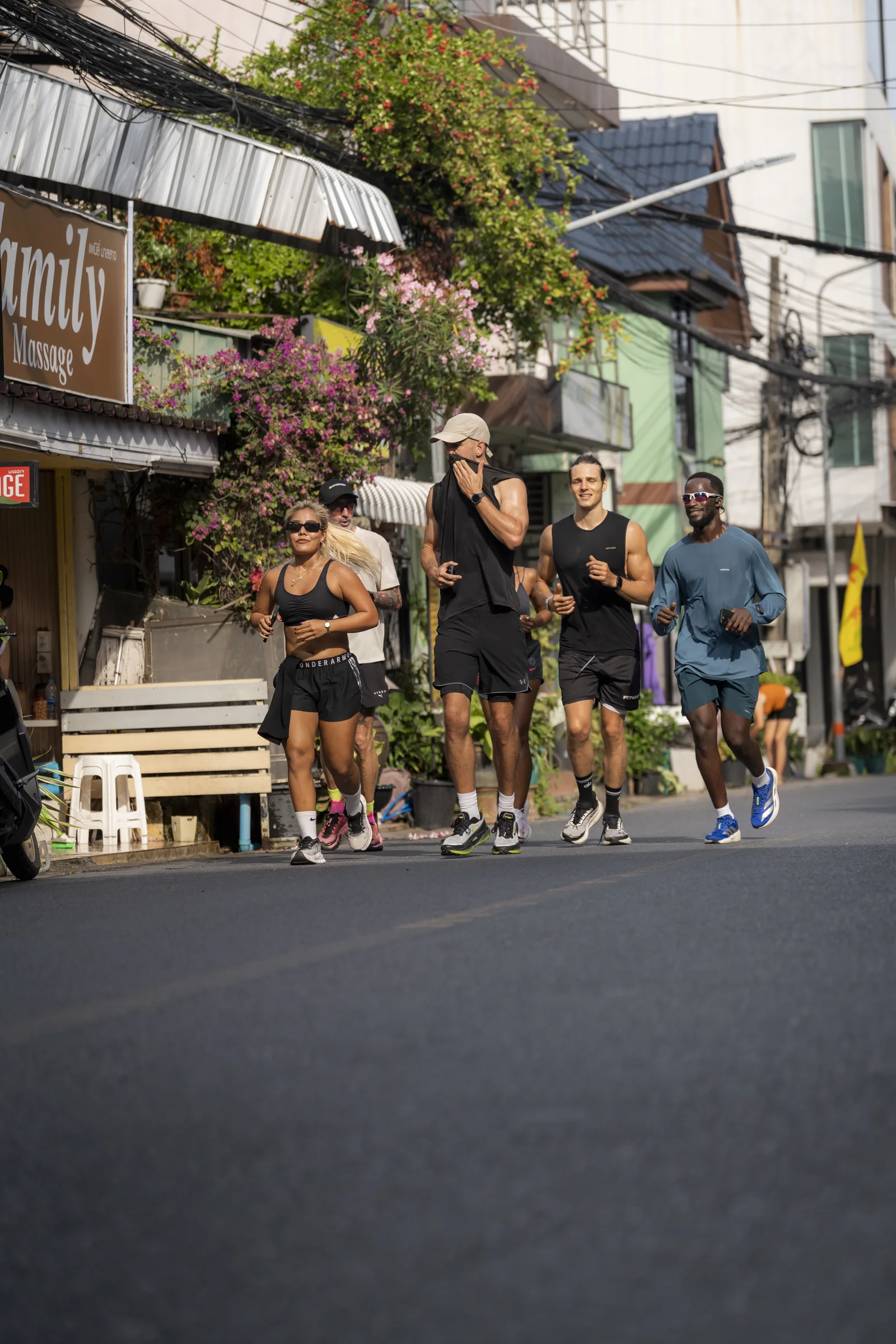 EMPOWER Run Club group running past flowering trees in Kamala