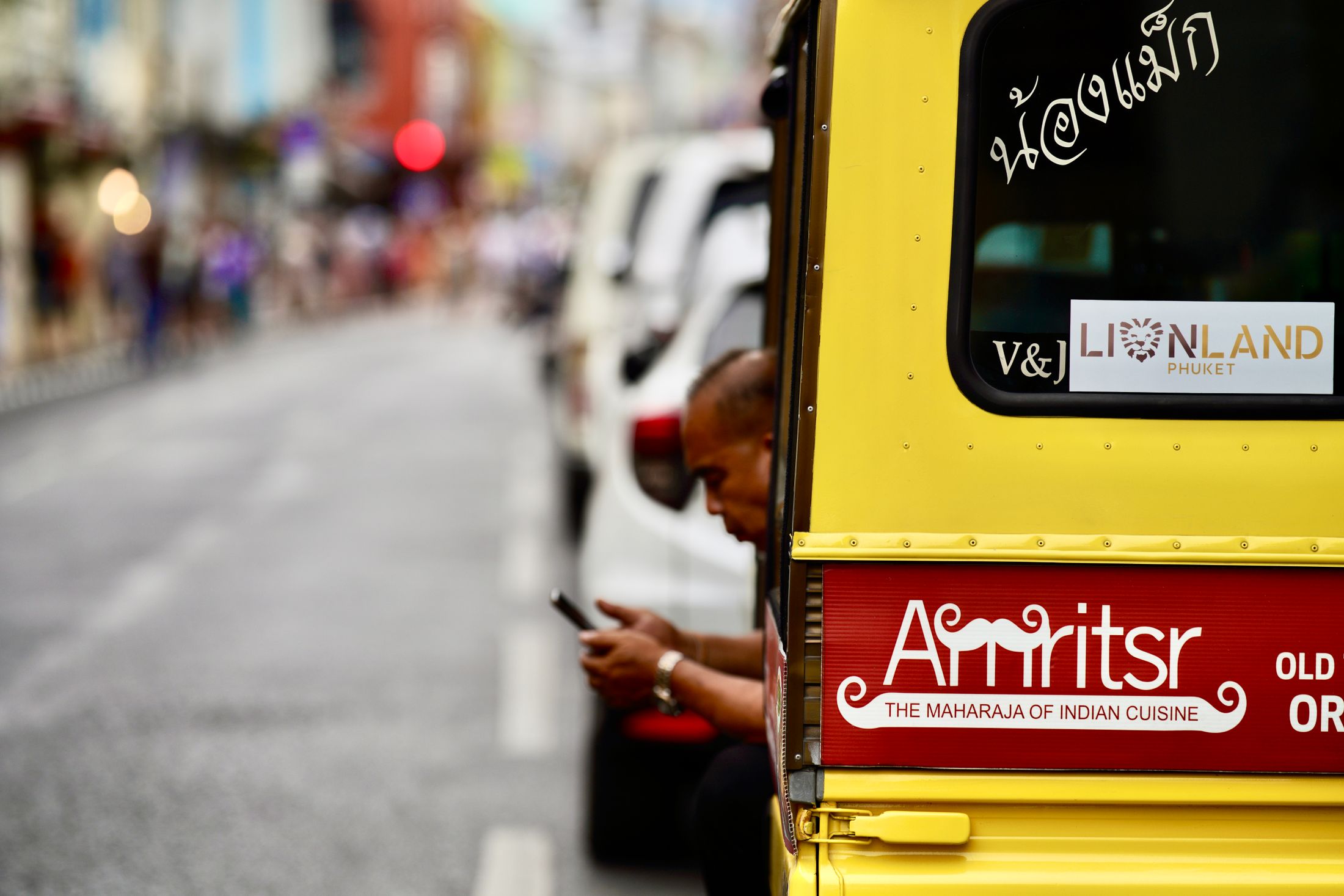 A colourful yellow tuk-tuk on a street in Phuket
