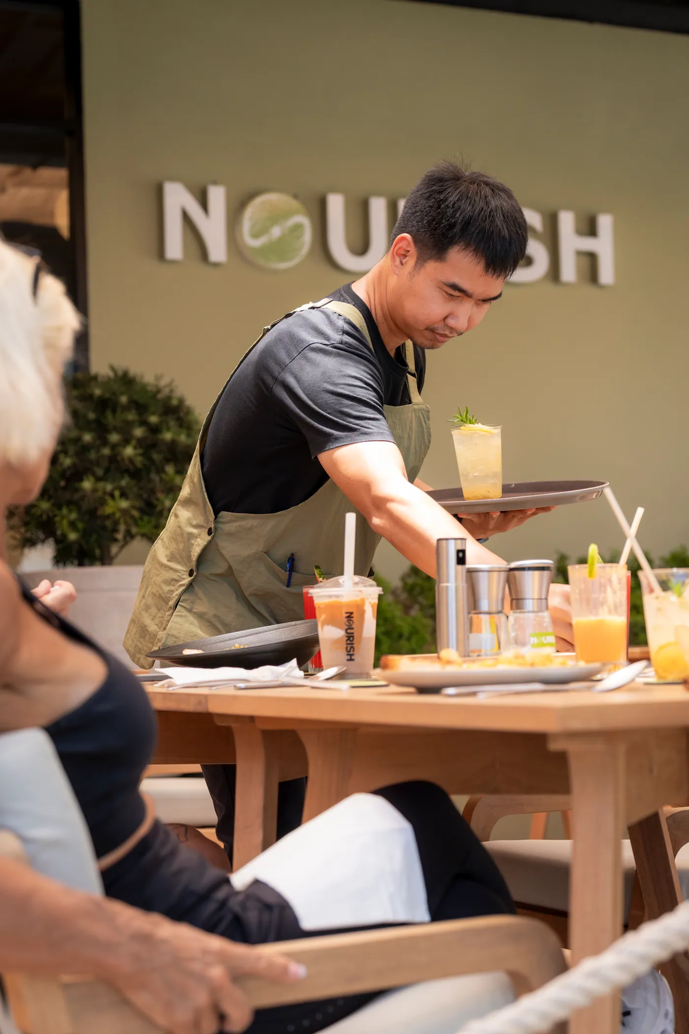 NOURISH team member serving guests on the terrace