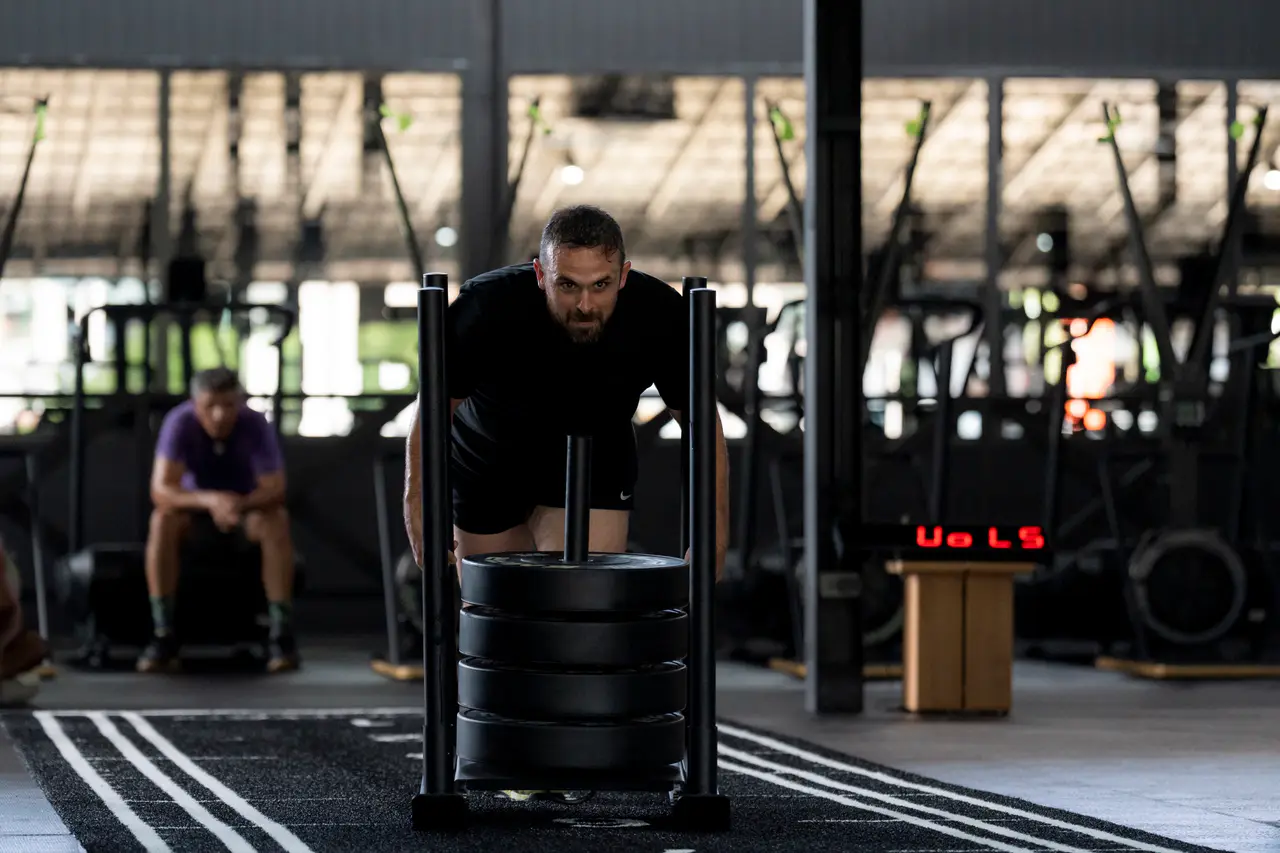 Athlete pushing a weighted sled during a HYROX class at EMPOWER